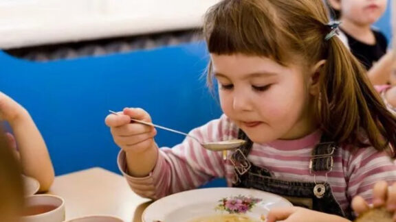 O fetiță mănâncă la grădiniță