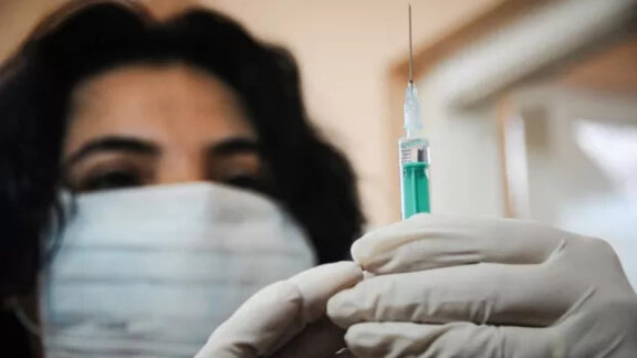 O femeie ce pregăteşte preparatul înainte de vaccinare